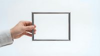Hand holding empty black picture frame against white background for mockup design and presentation purposes.