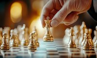 Hand moving golden queen chess piece on board with strategic positioning, warm ambient lighting creating dramatic atmosphere for business competition.