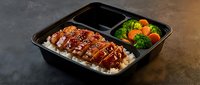 Sliced glazed duck breast with sesame seeds served over rice, accompanied by steamed broccoli and carrots in a black compartment tray for meal prep.