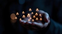 Glowing user icons floating above cupped hands in dark background, representing social network, human resources and digital community connection concept.