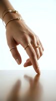Elegant female hand with gold jewelry bracelets and rings touching reflective surface in soft natural light for luxury fashion and accessories concepts.