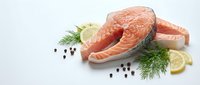 Fresh salmon steaks with dill, lemon slices and peppercorns on white background. Raw fish fillets for healthy cooking and gourmet cuisine preparation.