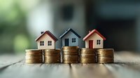 Small model houses placed on stacks of gold coins against blurred background, representing real estate investment, property market, and housing finance concept.