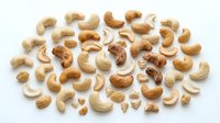 Raw cashew nuts scattered on white background isolated for healthy snacking and cooking ingredients in organic food preparation.