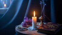 Mystical fortune telling setup with burning candle, crystal ball, tarot cards and incense creating atmospheric mood for spiritual readings and divination.