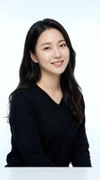 Young Asian businesswoman in black v-neck sweater smiling confidently on white background, professional headshot for corporate marketing materials.