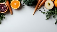 Fresh organic produce arrangement with citrus fruits, carrots, broccoli and herbs on white background with copy space for menu design or healthy eating concept.