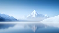 Serene mountain peak reflecting in calm lake waters with morning mist creating ethereal atmosphere. Minimalist winter landscape in blue tones.