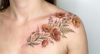 Elegant floral tattoo with orange poppies and delicate leaves adorning woman's shoulder and chest area showcasing botanical ink art design.