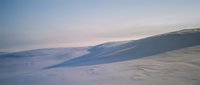 Serene winter landscape with snow-covered rolling hills and soft pastel sky at dawn or dusk creating peaceful arctic wilderness scenery for nature backgrounds.