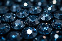 Shimmering dark blue crystals with bokeh light effects create mesmerizing abstract pattern. Macro photography captures faceted surfaces reflecting white glowing orbs.