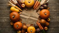 Autumn harvest wreath with pumpkins, corn, carrots and nuts arranged in circle on rustic wooden background for seasonal decoration and thanksgiving celebration.