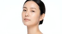 Young Asian woman with natural makeup and glowing skin on white background for beauty and skincare advertising campaigns.