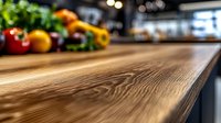 Rustic wooden kitchen counter surface with natural wood grain texture in selective focus, fresh vegetables and produce blurred in background for food preparation space.