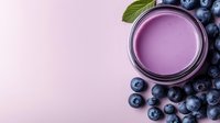 Fresh blueberry smoothie in glass jar surrounded by organic berries and green leaves on soft pink background for healthy lifestyle and nutrition.