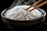 Steamed white rice in rustic ceramic bowl with wooden chopsticks against dark background, ready for Asian cuisine dishes.
