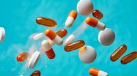 Colorful pharmaceutical capsules and pills floating against bright turquoise background. Medical healthcare concept for drug treatment and medication therapy.