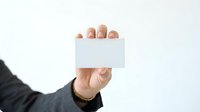 Caucasian male professional holding blank white business card or namecard in hand against neutral background for corporate branding and marketing purposes.