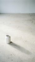 Small white ceramic vase on a concrete floor casting a long shadow, minimalist interior concept with neutral tones and empty space.
