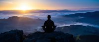 Man meditating on mountain peak at sunrise with misty valleys below, peaceful morning landscape for wellness and mindfulness concepts.