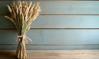 Rustic wheat bundle tied with twine against weathered blue wooden planks background, creating farmhouse atmosphere on wooden surface.