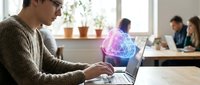 Young professional woman with glasses using laptop with glowing AI brain hologram in modern coworking office space for technology and innovation concepts.
