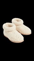 Pair of cream knitted booties with rolled cuffs and tan soles, isolated on transparent background. Ready for e-commerce, product mockups, fashion catalogs, t-shirt designs, and print-on-demand applications.