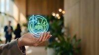 Businessman holding glowing neon hologram of industrial factory icon with gears and technology symbols, representing smart manufacturing and digital innovation in modern business environment.