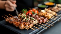 Grilled meat and seafood skewers with herbs on dark slate plate, variety of kebabs including chicken, shrimp and vegetables in rustic setting for barbecue.