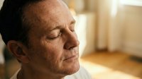 Middle-aged man with light skin tone and brown hair in profile, eyes closed in contemplation or meditation, warm indoor lighting, suitable for wellness and mindfulness concepts.