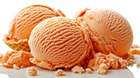 Creamy orange sherbet ice cream scoops with crushed cookie crumbles scattered on white surface, fresh frozen dessert photographed with soft lighting.
