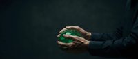 Businessman hands protecting green earth globe on dark background symbolizing environmental responsibility and corporate sustainability commitment.