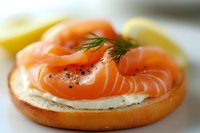 Fresh smoked salmon and cream cheese on toasted bagel with dill garnish and black pepper, macro food photography with soft selective focus.