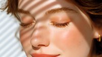 Young woman with closed eyes enjoying warm sunlight on face creating natural shadow patterns for skincare and wellness concepts.