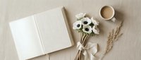 Open blank notebook with white anemone flowers, coffee cup and wheat stems on neutral background for journaling, planning and creative writing projects.