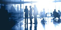 Silhouettes of business professionals networking in modern office with blue tinted lighting, creating atmosphere of corporate collaboration.