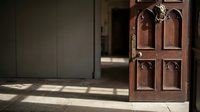 Ornate wooden door with decorative metal hardware casting shadows on tiled floor in traditional interior architectural setting for home design projects.