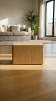 Cardboard box on wooden floor in bright living room with beige sofa, green plant, and window light for shipping, delivery, moving, storage, and logistics concepts.