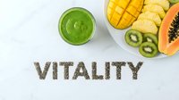 Green smoothie with tropical fruits and chia seed lettering spelling vitality on marble surface, healthy lifestyle and nutrition concept.