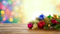 Festive Christmas ornaments and pine branches on wooden surface with colorful bokeh background for holiday greeting cards and seasonal designs.
