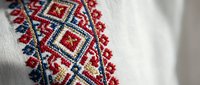 Traditional Ukrainian embroidery with red and blue geometric patterns on white linen fabric. Folk art needlework design for cultural clothing and textile crafts.