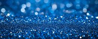Shimmering blue glitter background with bokeh effect and scattered sparkles creates magical festive atmosphere for holiday designs and celebrations.