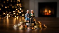 Elderly couple figurines sitting on stacks of coins with warm bokeh lights and fireplace background representing retirement savings and financial planning.