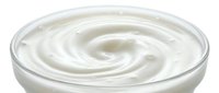 Creamy white yogurt or sour cream swirl in glass bowl, close-up view for food and dairy product marketing.