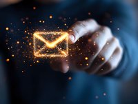 Glowing envelope icon with sparkles and light effects floating above hand in dark background, representing digital communication and email marketing concept.
