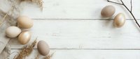 Natural organic eggs in neutral tones scattered on rustic white wooden background with twine and branches, farm fresh concept for cooking and baking.