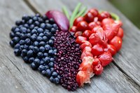 Fresh heart-shaped arrangement of blueberries, blackberries and red hot chili peppers on rustic wooden background, selective focus macro shot for food design.