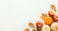 Autumn harvest composition with pumpkins, apples and oak leaves on neutral background with copy space for seasonal design projects.