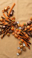 Halloween candy assortment with chocolate treats, orange and black licorice sticks, pumpkin candies on brown paper background for seasonal celebrations.