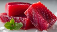 Fresh raw tuna steaks with green herbs on ice, premium sashimi grade fish fillets for gourmet cooking and Japanese cuisine preparation.